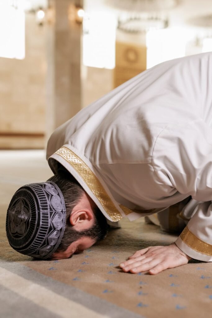 About A Muslim man in traditional attire praying inside a mosque, showcasing cultural reverence.